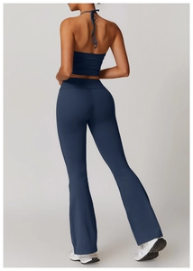 Rear view showing the open-back halter top and high-waisted flared yoga pants in dark blue
