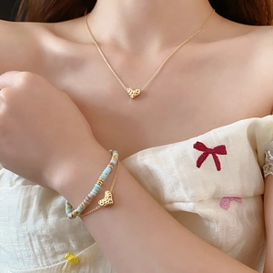 Detail of model wearing a gold heart pendant necklace with matching beaded bracelet set