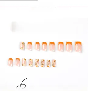 Macro detail of 24pcs press-on nails with orange French tips and gold glitter marble patterns