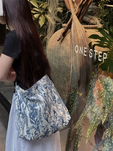 Detail of large canvas tote bag featuring blue vintage floral prints in outdoor sunlight