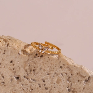 Detailansicht verstellbarer goldener Schmetterlingsring mit Kristallen auf Naturstein