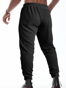 Close-up of black waffle knit joggers fabric texture and back pocket detail on men's pants