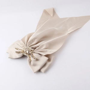 Detail of champagne gold satin bow hair clip with luxury rhinestone centerpiece decor