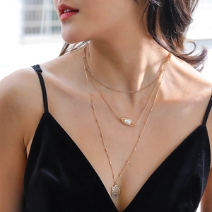 Close-up of layered gold necklace featuring a pearl pendant and hammered metal square tag