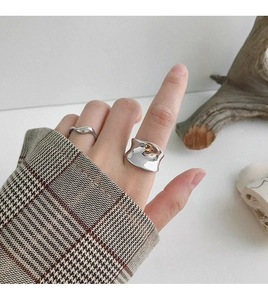 Nahaufnahme eines breiten silbernen gewellten Rings an der Hand im minimalistischen Stil