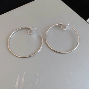 Close-up of large silver hoop clip-on earrings with comfortable clear silicone pads
