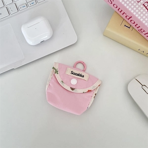 Detailed view of pink fabric earphone pouch with floral trim and Sozakka label on a white desk