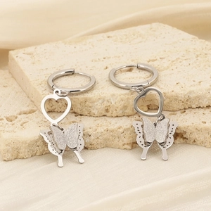 Macro view of silver heart earrings with frosted and cutout butterfly charms on fabric