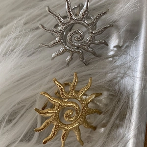 Exaggerated sun-shaped open rings in gold and silver finish with spiral texture