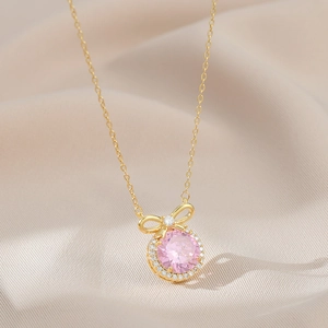 Nahaufnahme der goldenen Schleife mit rosa Edelstein und Zirkonia auf Seide