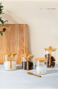 Close-up of airtight borosilicate glass storage jars with bamboo lids and spoons in kitchen