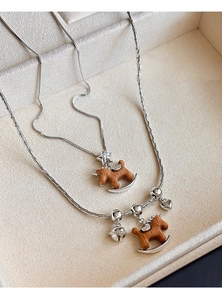 Détail de pendentifs cheval à bascule en bois avec breloques cœur et cloche sur chaînes