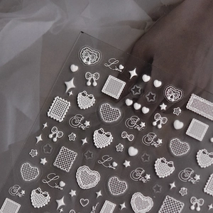 Detailed macro view of white embossed 3D nail stickers with lace heart and star patterns