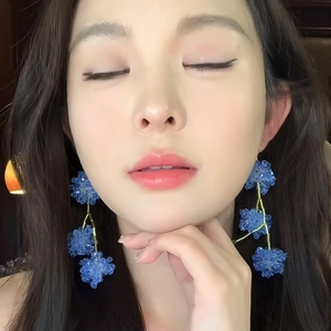Détail d'un mannequin portant des boucles d'oreilles fleurs en perles bleues et fil doré