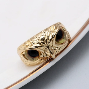 Detailed close-up of golden owl ring with amber resin eyes and textured metal feathers