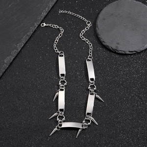 Detail of silver hip hop chain necklace with metal plates and spike charms on stone