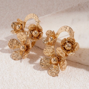 Gros plan détaillé de boucles d'oreilles fleurs dorées à texture de métal martelé