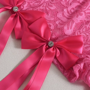 Vue détaillée de dentelle rose avec deux nœuds en satin ornés de centres en strass