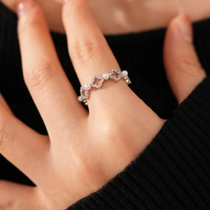 Vue détaillée d'une bague trèfle argentée avec perles et zircons sur une main