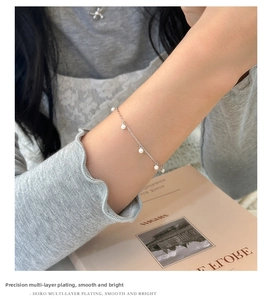 Primo piano di un bracciale minimalista in argento con perle bianche sul polso