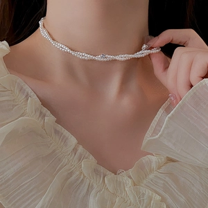 Dettaglio di una collana di perle bianche a doppio strato con perle argentate sul collo