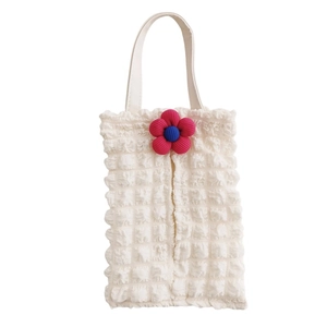 Detail of white popcorn fabric car tissue box with a red knitted flower and leather handle