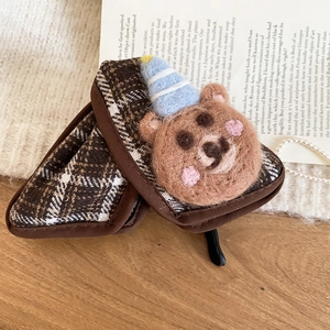 Close-up of brown plaid fabric texture with a cute handmade felt bear decoration