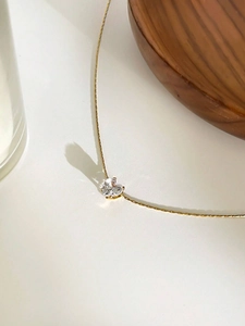 Detailed close-up of a heart-shaped zircon pendant on a fine golden metal chain
