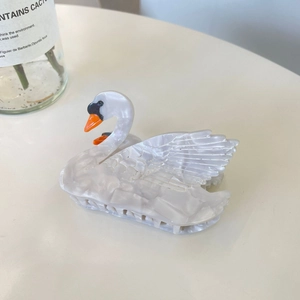 Macro view of white marble acetate swan hair claw clip with orange beak detail