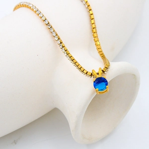 Elegant gold tennis chain necklace with a round blue birthstone pendant in 4-prong setting