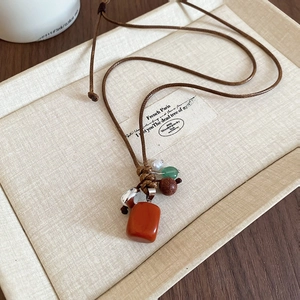 Detail of ethnic beaded necklace with red stone pendant on a beige jewelry tray