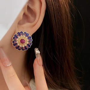 Macro detail of a vintage flower earring with blue enamel, pearl accents, and pink gemstone