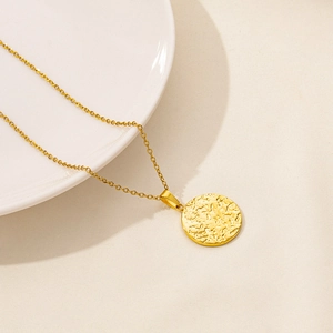Close-up of gold 18k plated stainless steel necklace with textured circular pendant