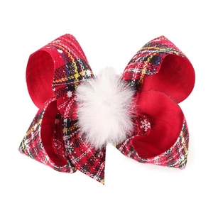 Detail of a 4-inch red plaid Christmas bow hair clip with a soft white pom-pom
