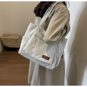 Detail of striped corduroy tote bag showing the texture and fashion leather tag
