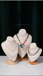 Three elegant necklaces displayed on velvet mannequin busts with round beech wood bases