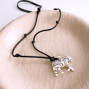 Close-up of zebra pendant with black and white stripes on a pink ceramic tray