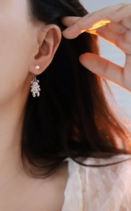 Detail view of the silver bear earring and white pearl shown from a side-wearing perspective