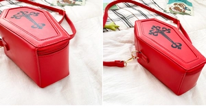 Close-up of red coffin-shaped crossbody bag with black gothic cross and zipper detail