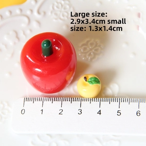 Miniature resin apple ornaments in red and yellow with precise measurement scale
