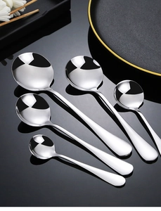Polished stainless steel round spoons in various sizes on black reflective surface