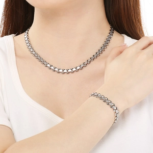 Detail view of silver link chain necklace and bracelet set on a female model