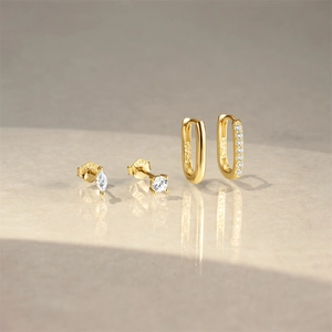Detail view of gold-plated S925 silver hoop earrings and stud set on stone surface