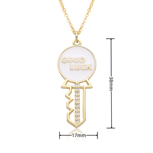 Detail of 18k gold heart key pendant with white enamel and Good Luck engraving