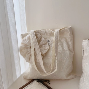 Creamy cotton tote bag with floral embroidery and oversized scrunchie detail on handle