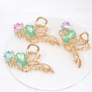 Close-up of three alloy flower hair claws with colorful lotus designs and pearls
