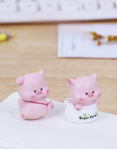 Detailed view of two cute pink resin pig figurines on a wooden desk for car interior decor