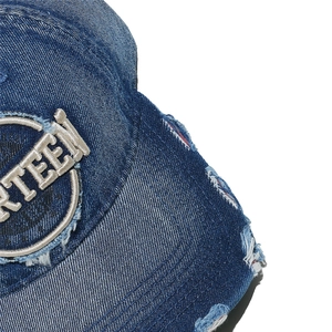 Detailed close-up of distressed denim baseball cap with Thirteen circular embroidery