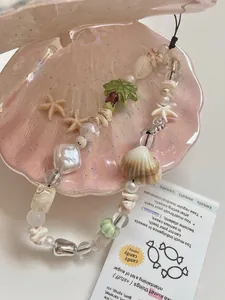Macro view of handmade summer style shell and coconut tree beaded phone charm lanyard.