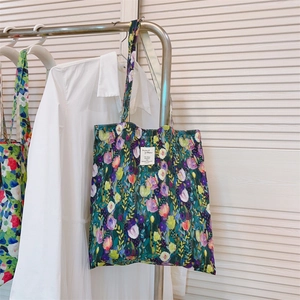 Close-up of a floral canvas tote bag featuring tulip prints and a woven brand label